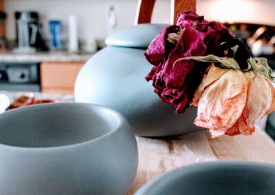 Detailed close-up of stoneware cups and teapot with withered flowers.