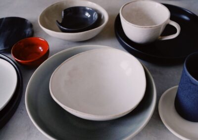 A variety of stylish ceramic dishware including bowls, cups, and plates arranged artistically on a table.