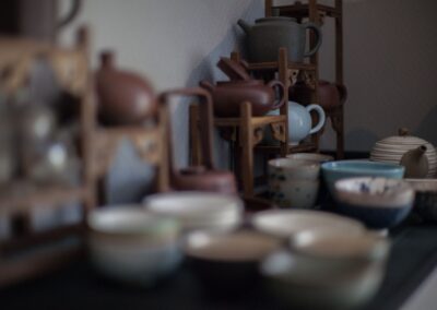 Various ceramic teapots in different shapes and traditional Asian cups placed on table in kitchen
