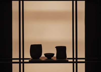 Minimalist display of ceramic vases on a wooden shelf against a soft background, showcasing elegant interior decor.